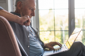 imagem de idoso usando seu laptop para saber mais sobre empréstimo consignado para aposentados