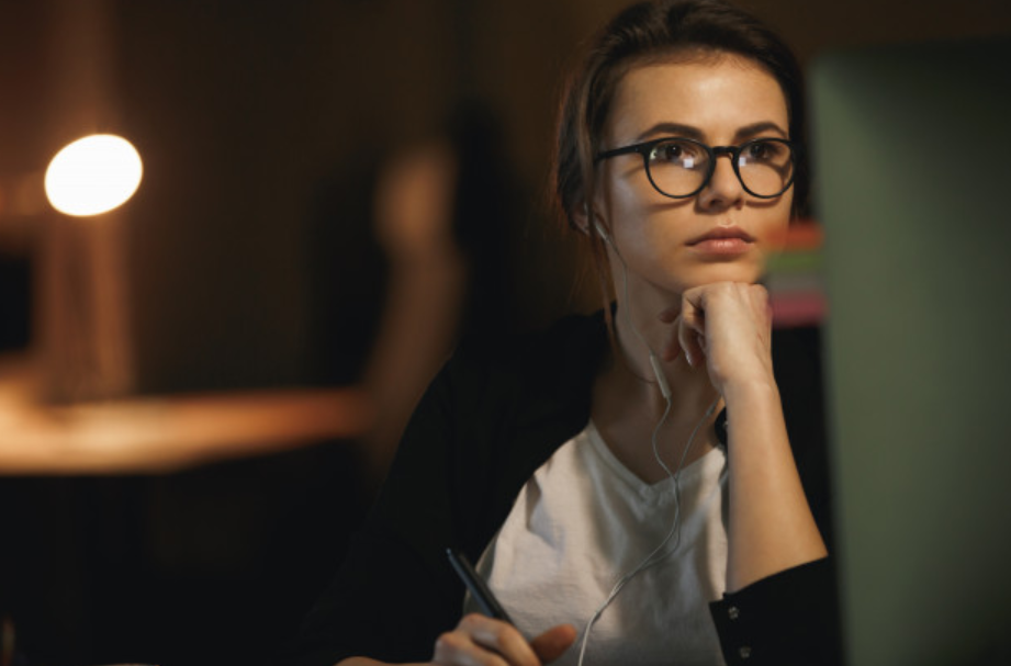mulher de óculos pensativa em frente a computador