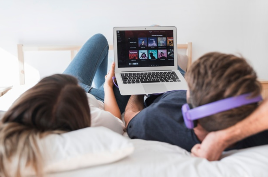 casal deitado em sua cama logado em uma plataforma de streaming 